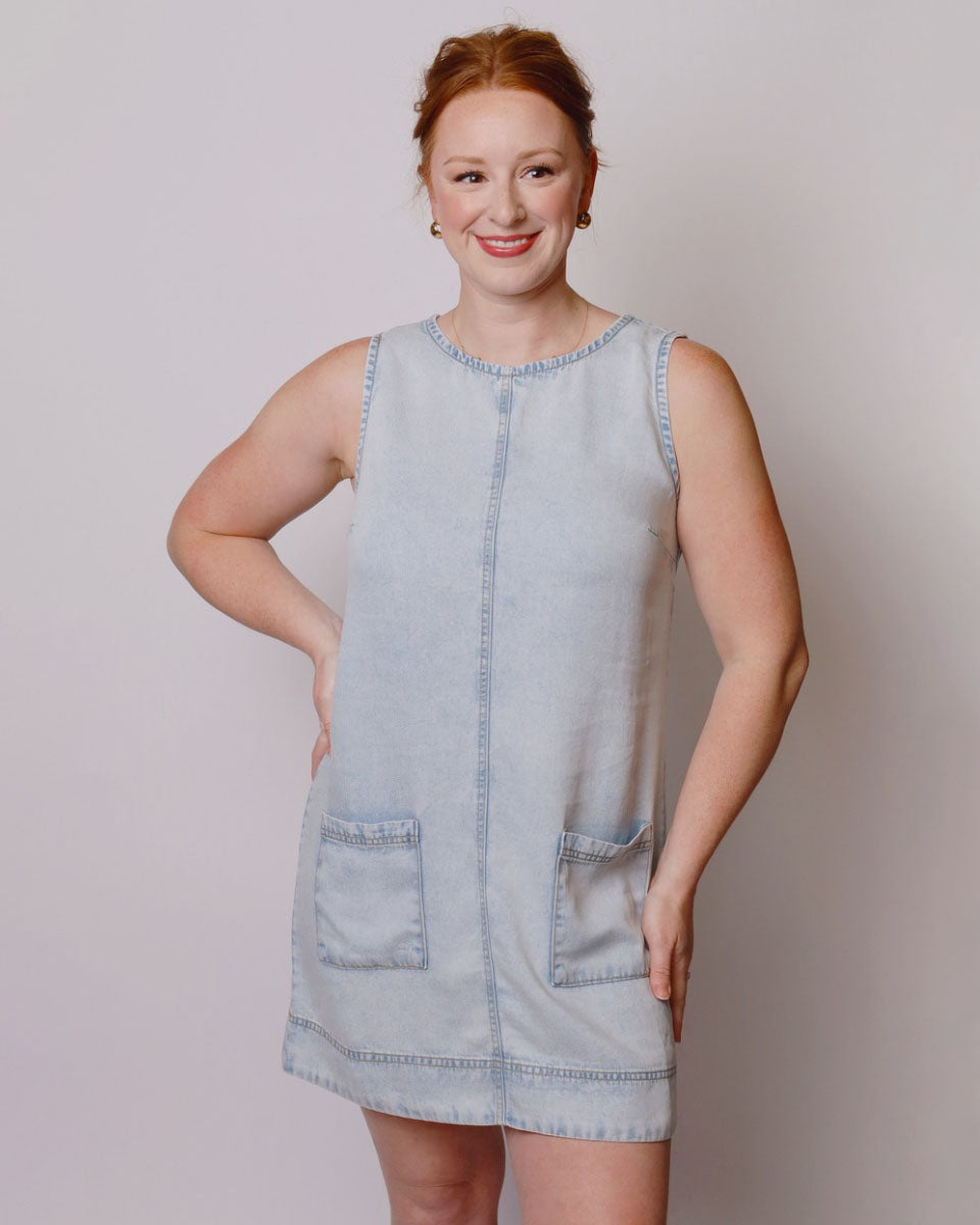 Woman wearing a light blue denim dress against a plain background