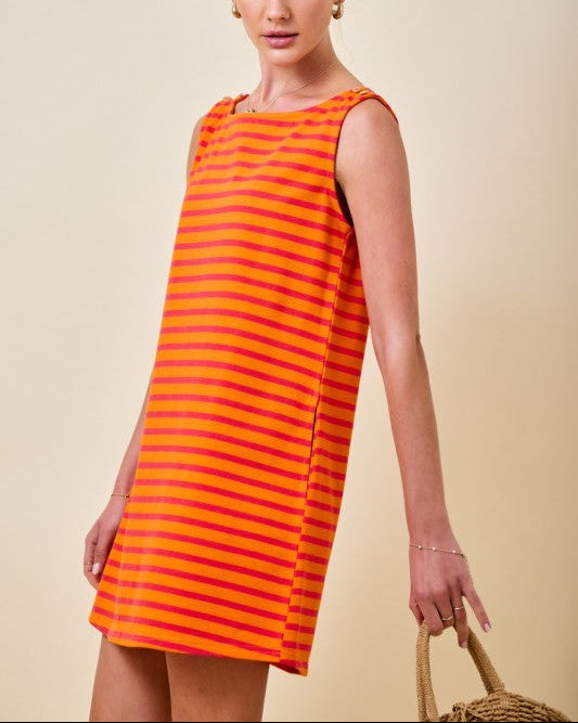 Woman wearing an orange and pink striped mini t-shirt dress on a neutral background side view