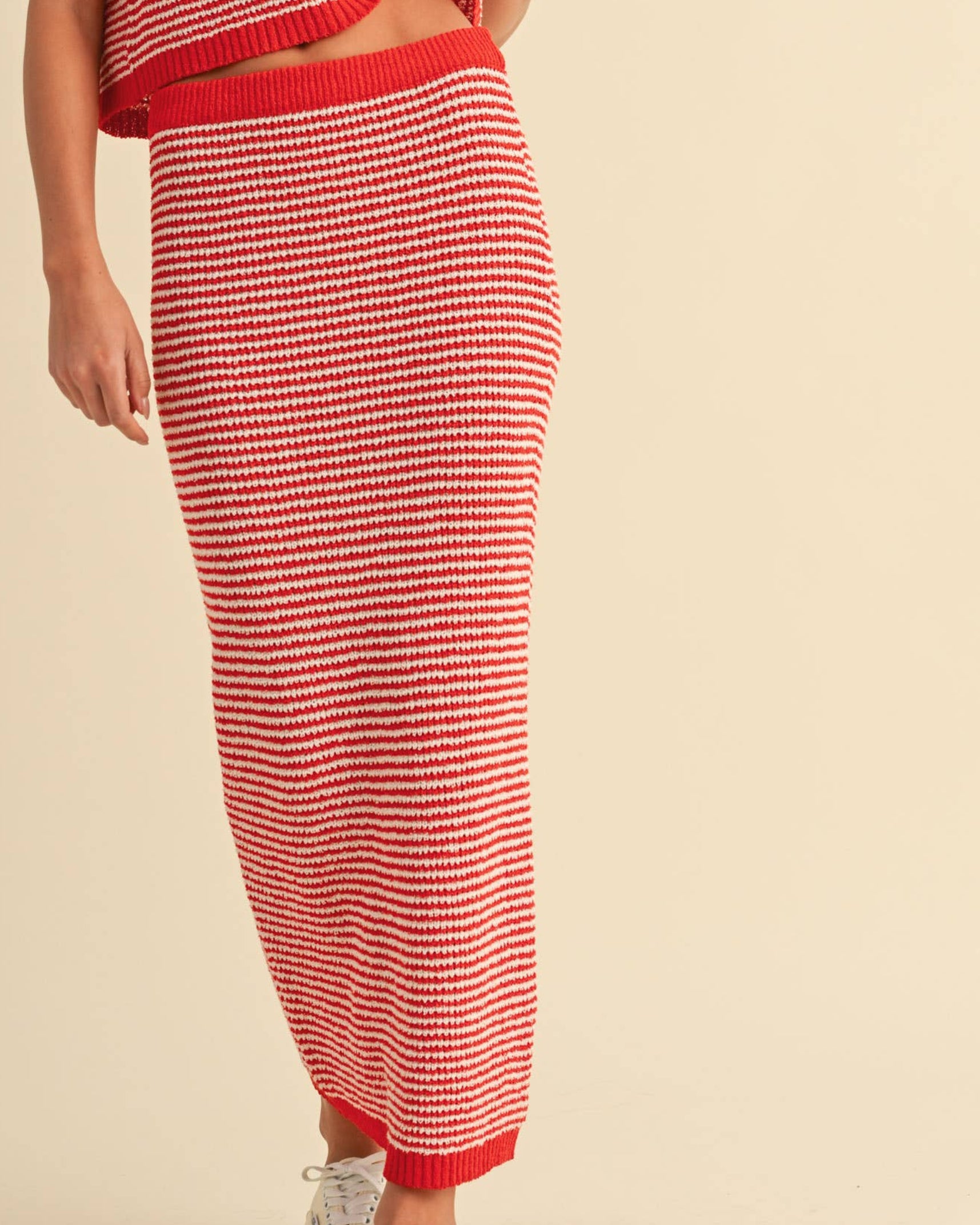 Woman wearing a red and white striped maxi skirt on a neutral background