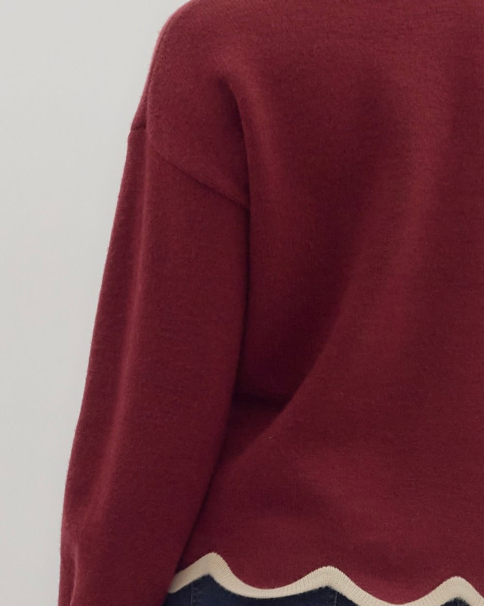 Close-up of a maroon sweater with a white and navy pattern on a light gray background