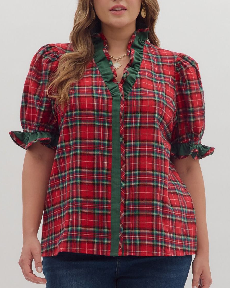 Woman wearing a red plaid shirt with green trim on a white background