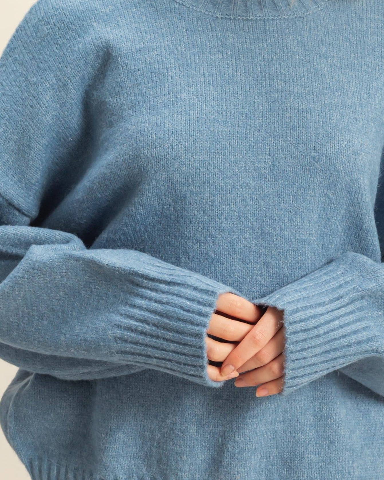Blue sweater worn by a person with a neutral background