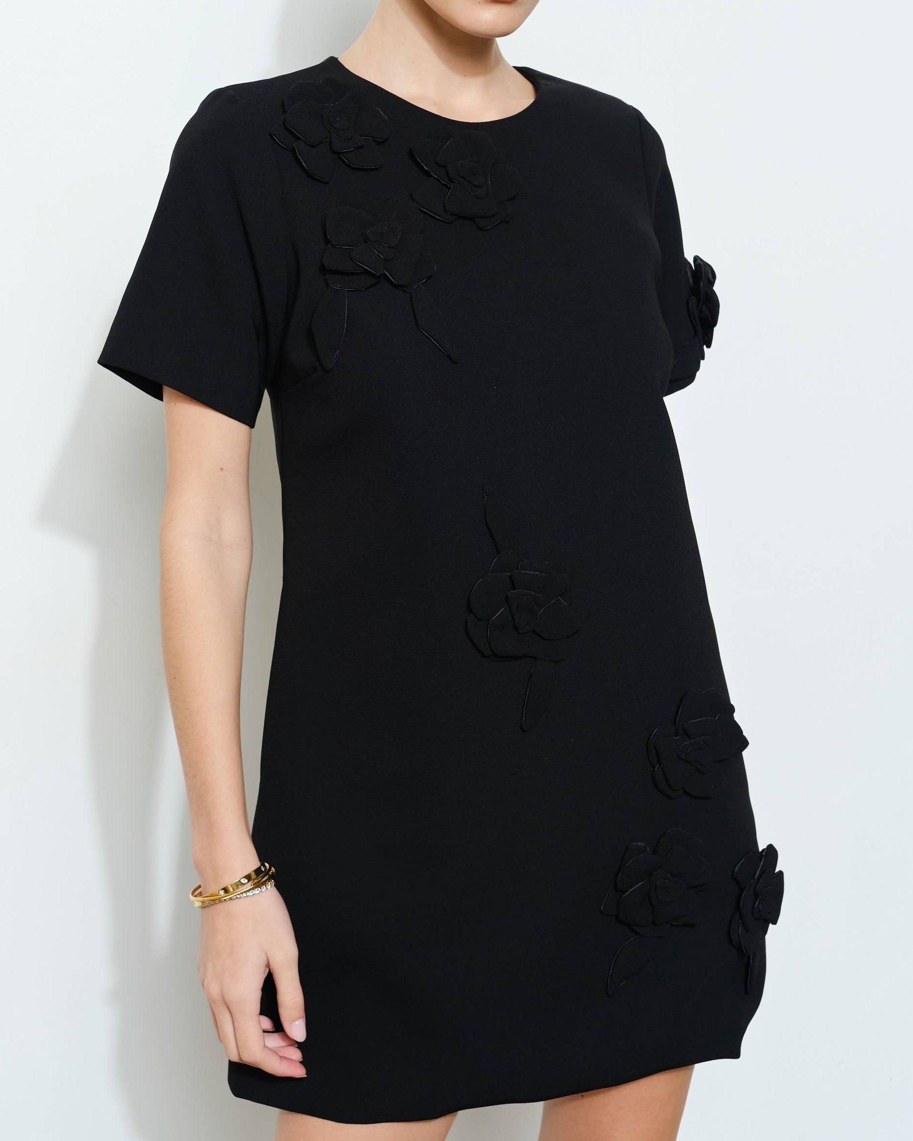 Woman wearing a black dress with floral details on a white background
