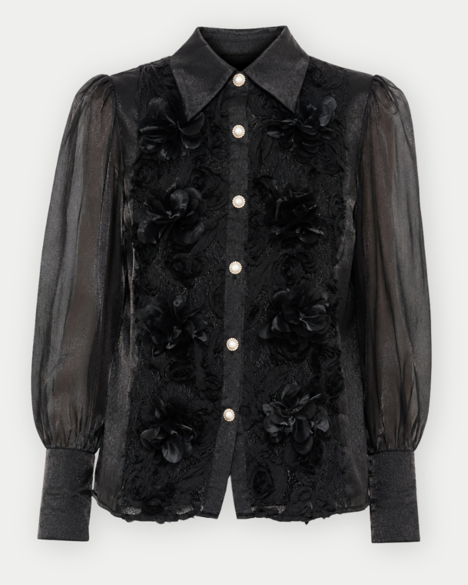 A black sheer mesh and floral lace button-up blouse with puff sleeves and white buttons, shown against a light gray background.