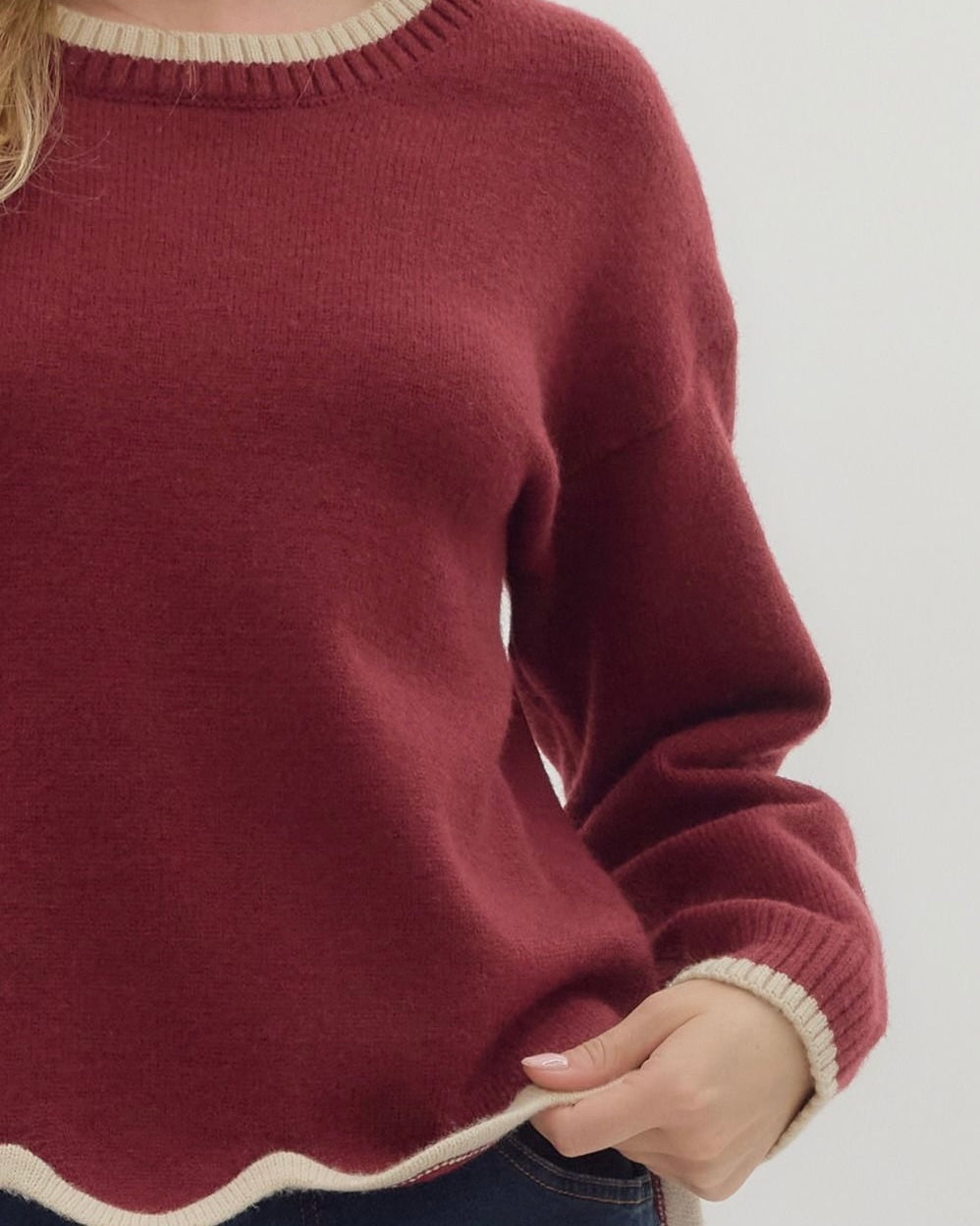 Maroon sweater with white trim on a neutral background