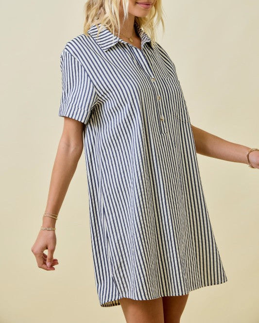 Woman wearing a black and white striped shirt dress against a beige background