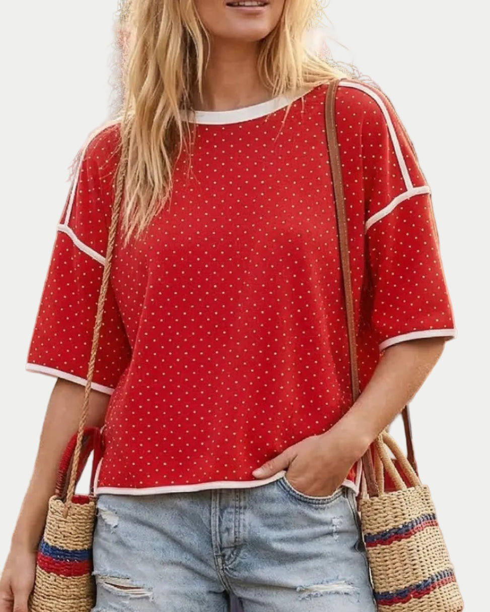 Model in a red top with white dots on a neutral background