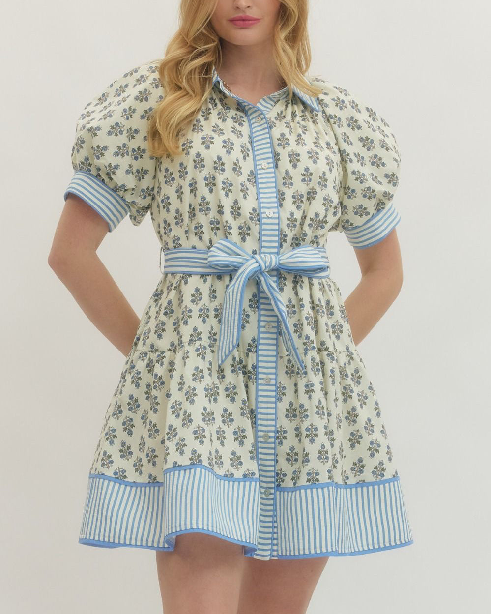 Woman wearing a floral dress with blue accents on a plain background