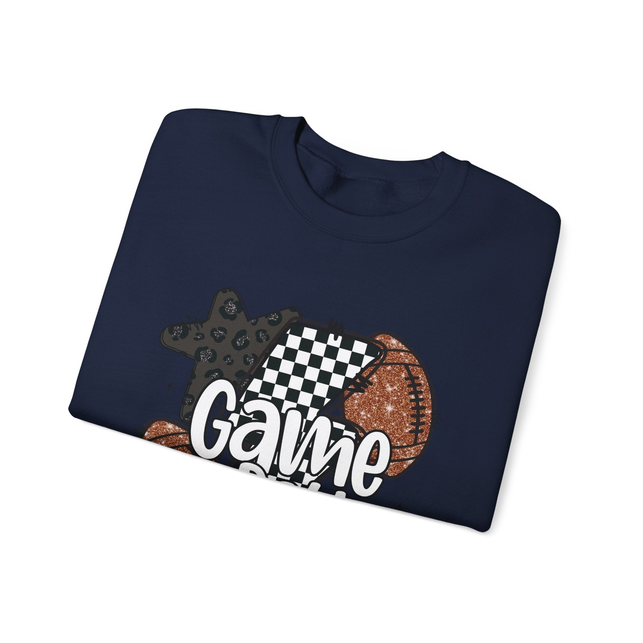 A folded navy crewneck t-shirt with a graphic print featuring a star, a checkered lightning bolt, a football, and the word 'Game' in white script, displayed on a clean white background.