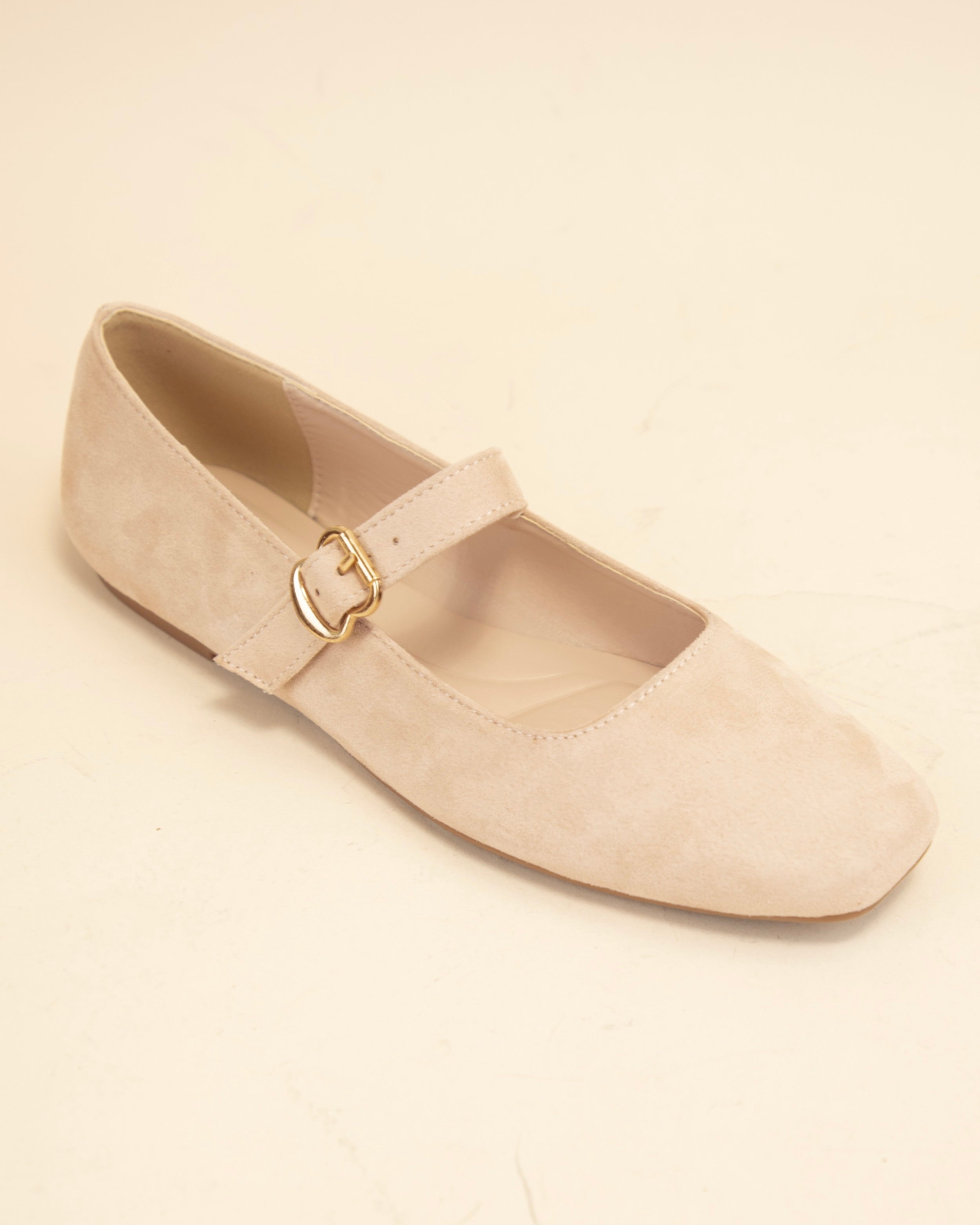 Beige flat shoe with a gold buckle on a beige background