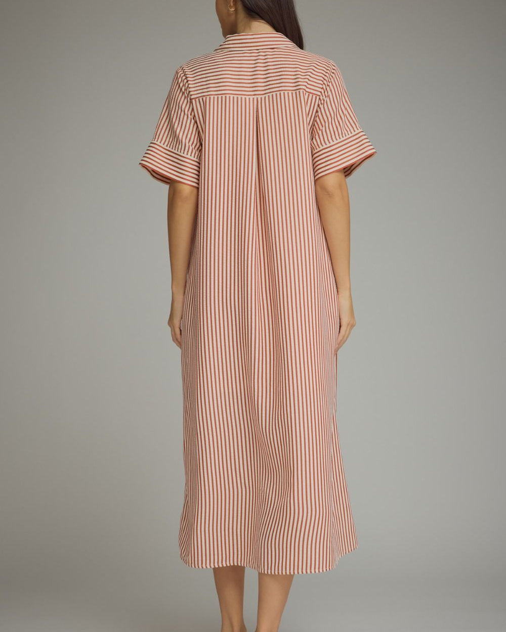 Woman wearing a striped dress against a plain background