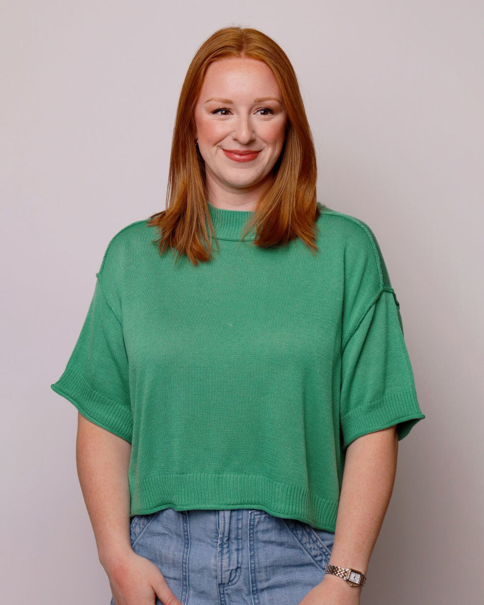Woman wearing a green sweater against a plain background