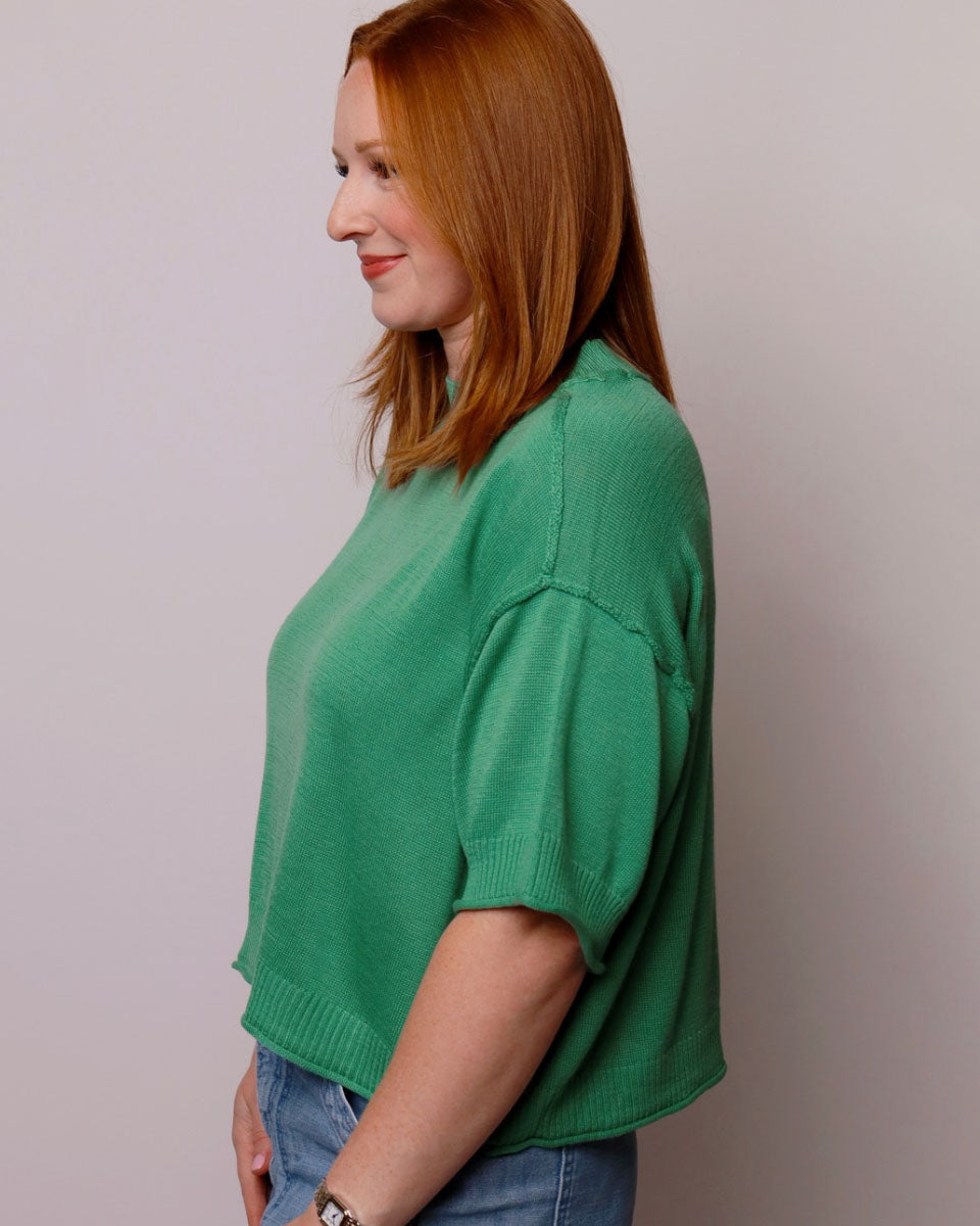 Woman wearing a green sweater against a plain background