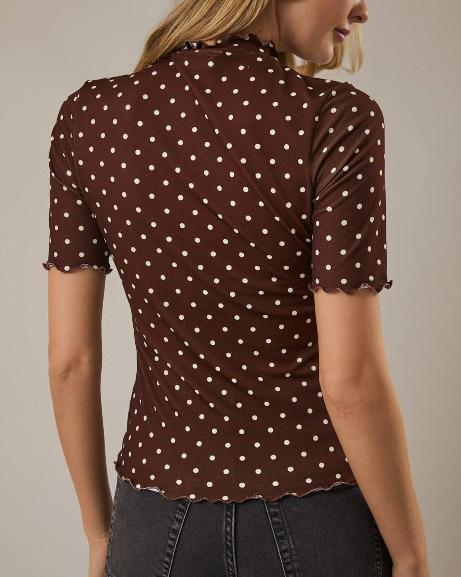 Woman wearing a brown polka dot blouse against a neutral background