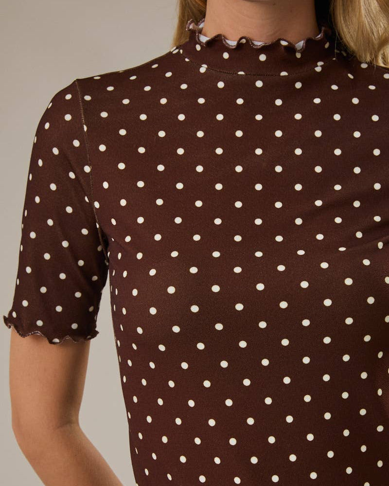 Woman wearing a brown polka dot blouse against a neutral background