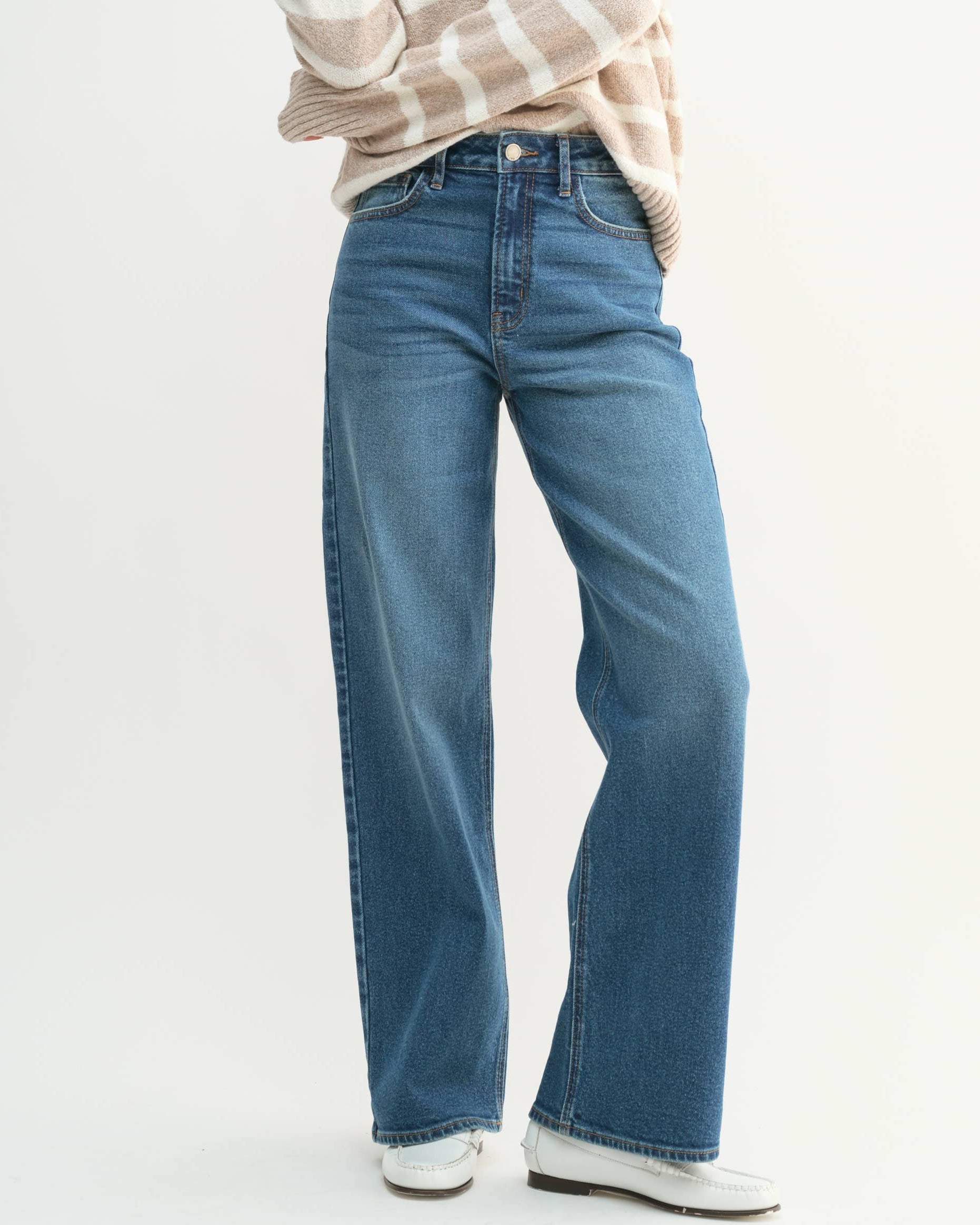 Woman wearing a striped sweater and blue jeans on a white background