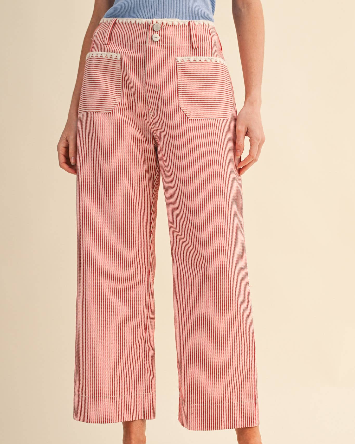 Person wearing red striped pants on a beige background front view