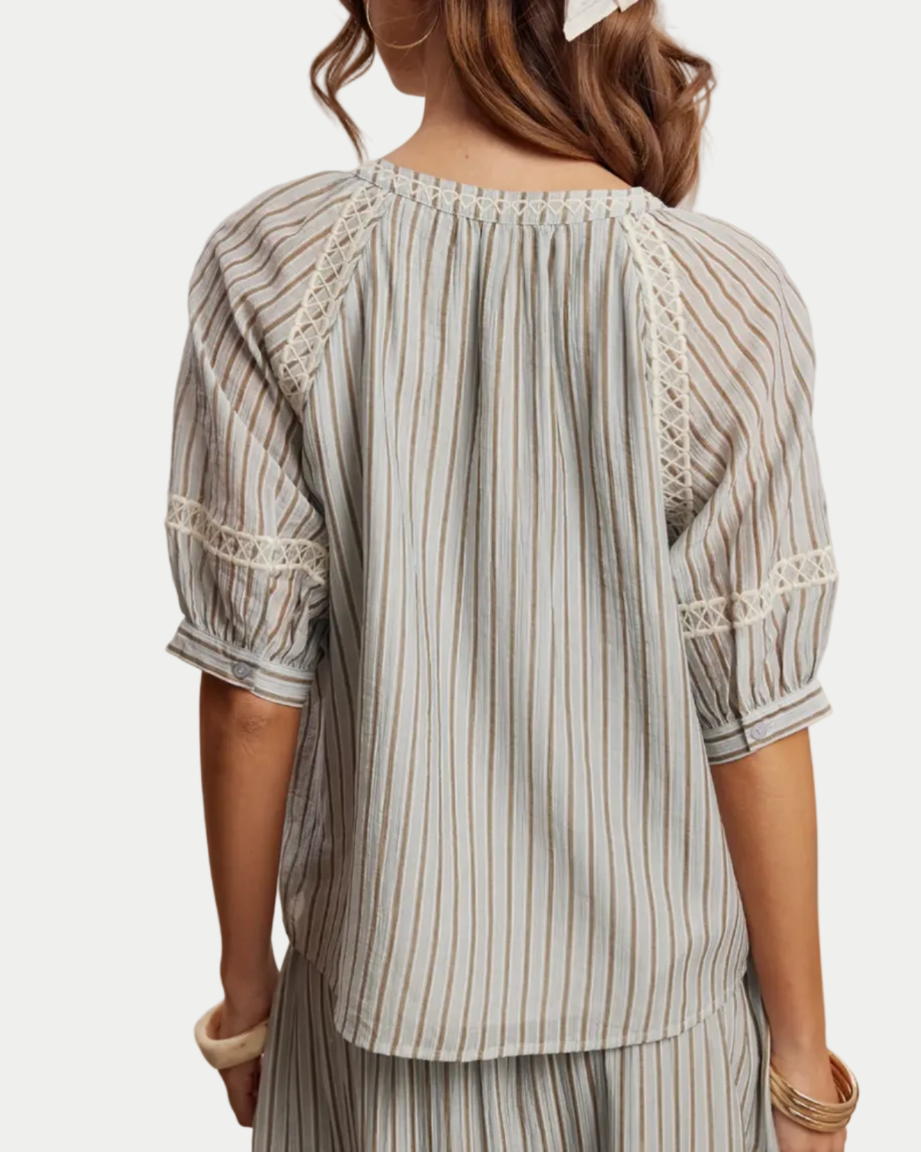 Person wearing a light blue striped top against a neutral background back view