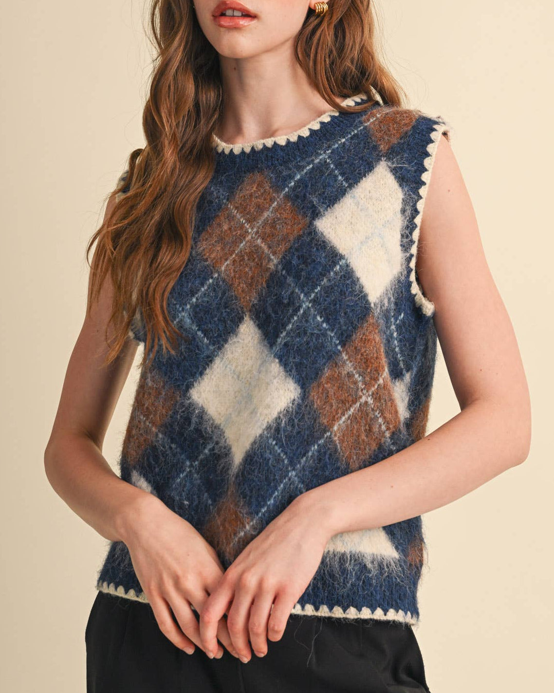 Model wearing a navy and brown argyle sweater vest on a neutral background