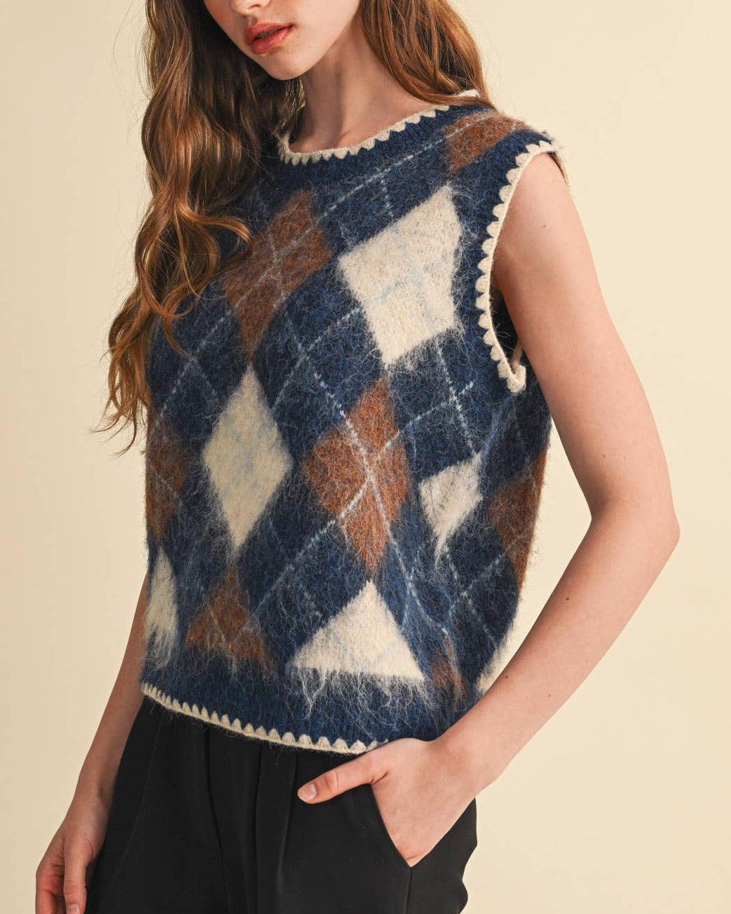 Model wearing a navy and brown argyle sweater vest on a neutral background