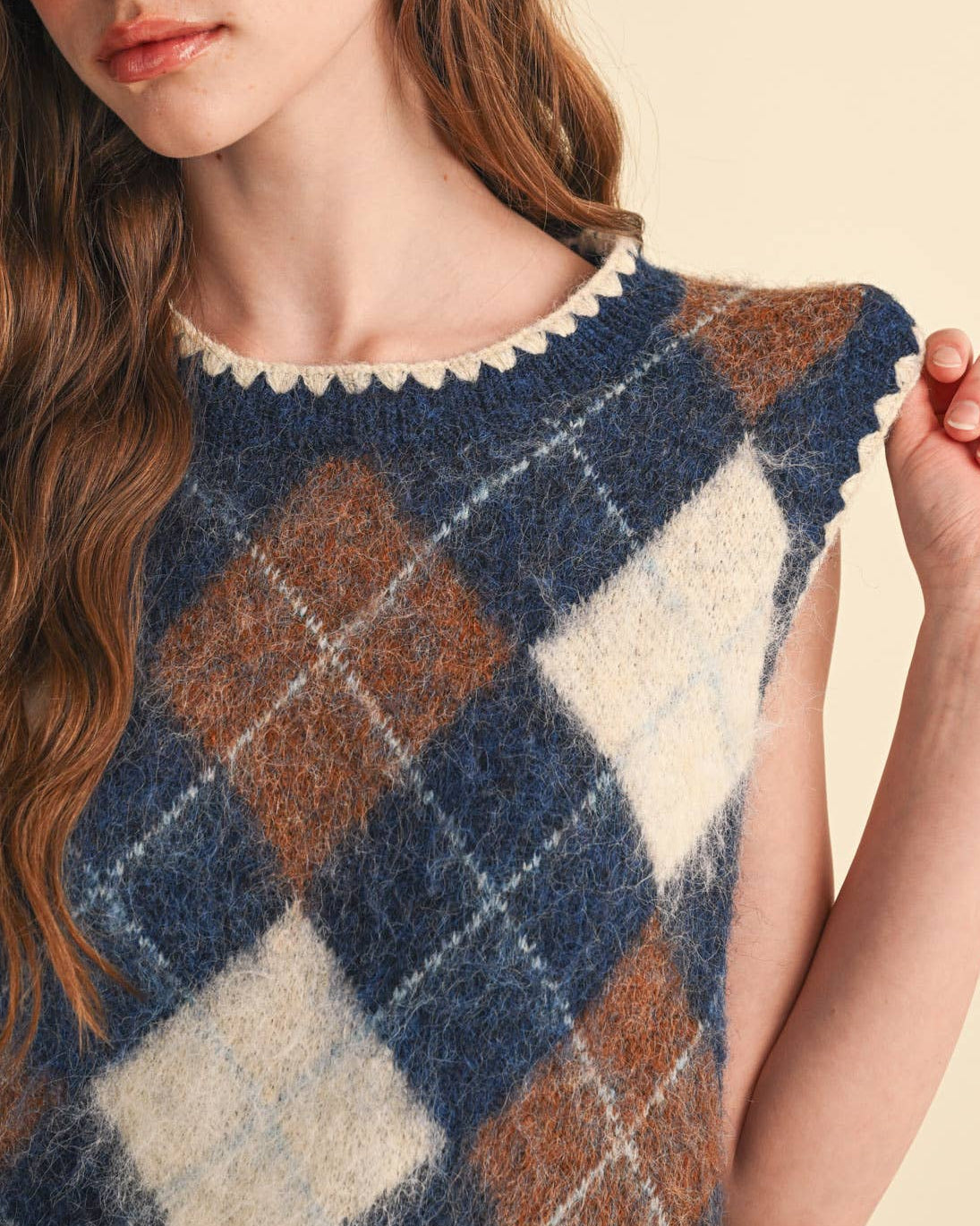 Model wearing a navy and brown argyle sweater vest on a neutral background