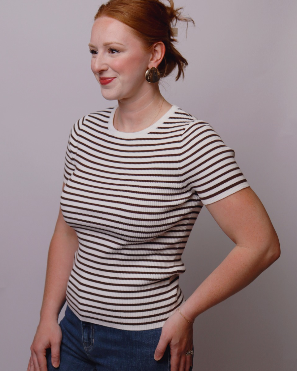 Woman wearing a black and white striped shirt against a plain background