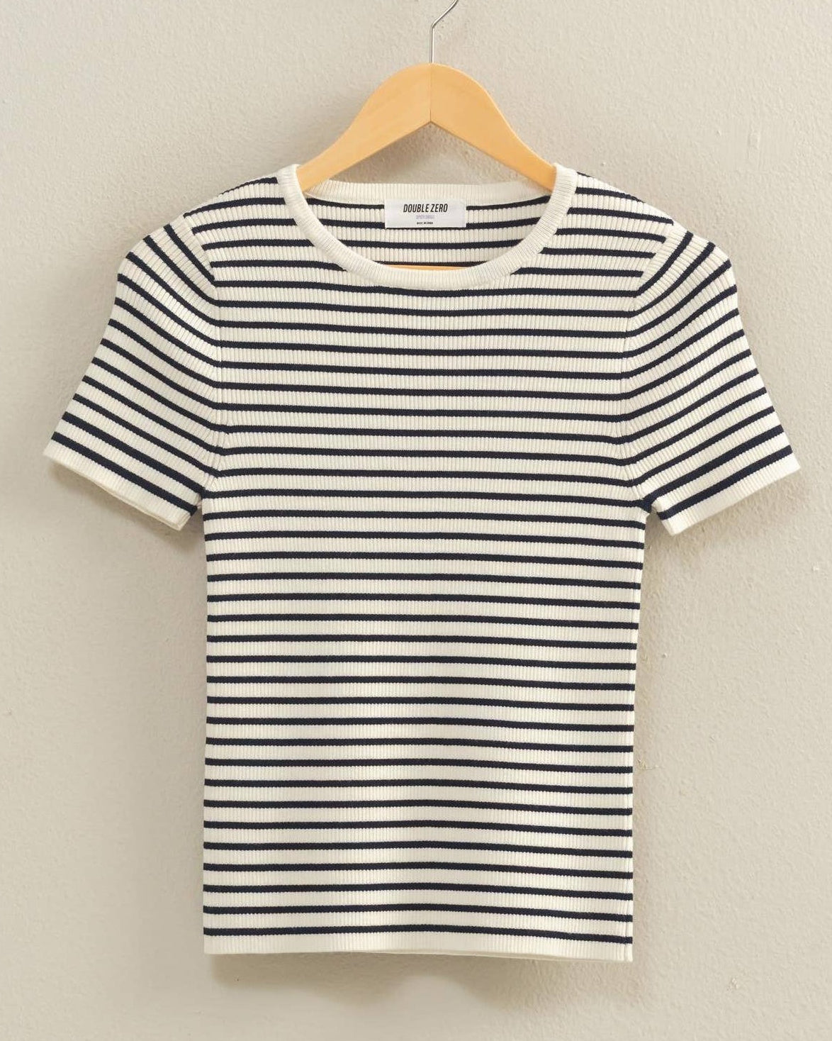 Navy and white striped t-shirt on a hanger against a neutral background
