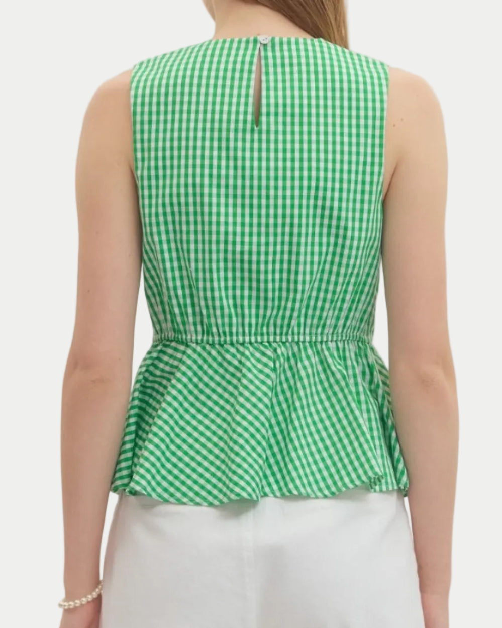 Woman wearing a green checkered peplum top and white shorts on a plain background.  unique sleeveles top.  Summer top.  Vacation Top.  Weekend wear.