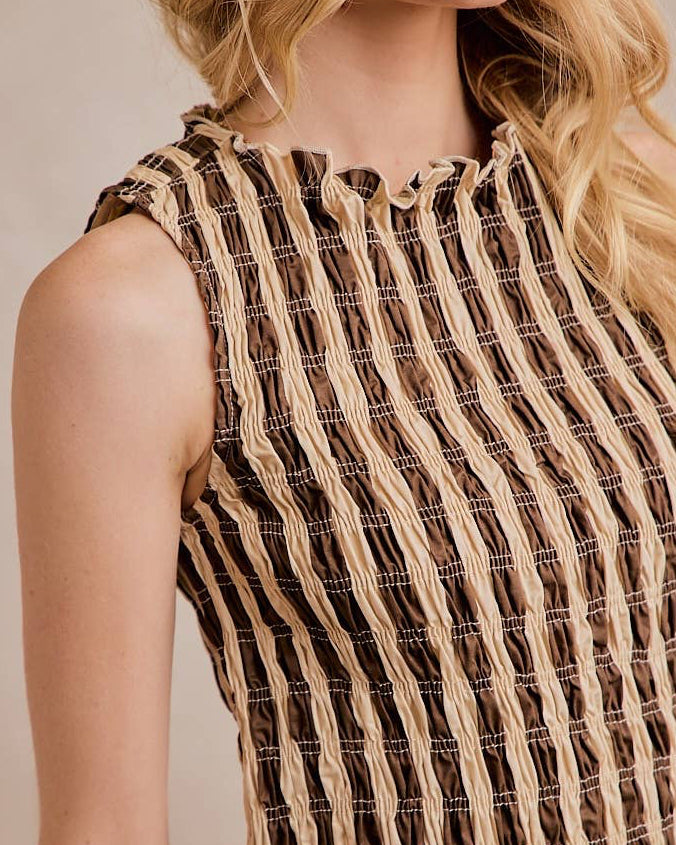 Woman wearing a sleeveless dress with a striped pattern on a plain background