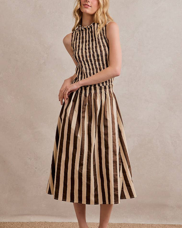 Woman wearing a black and beige striped dress against a neutral background