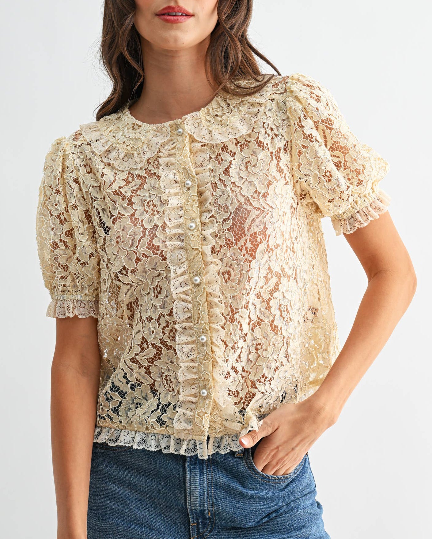 Woman wearing a lace top and blue jeans on a white background