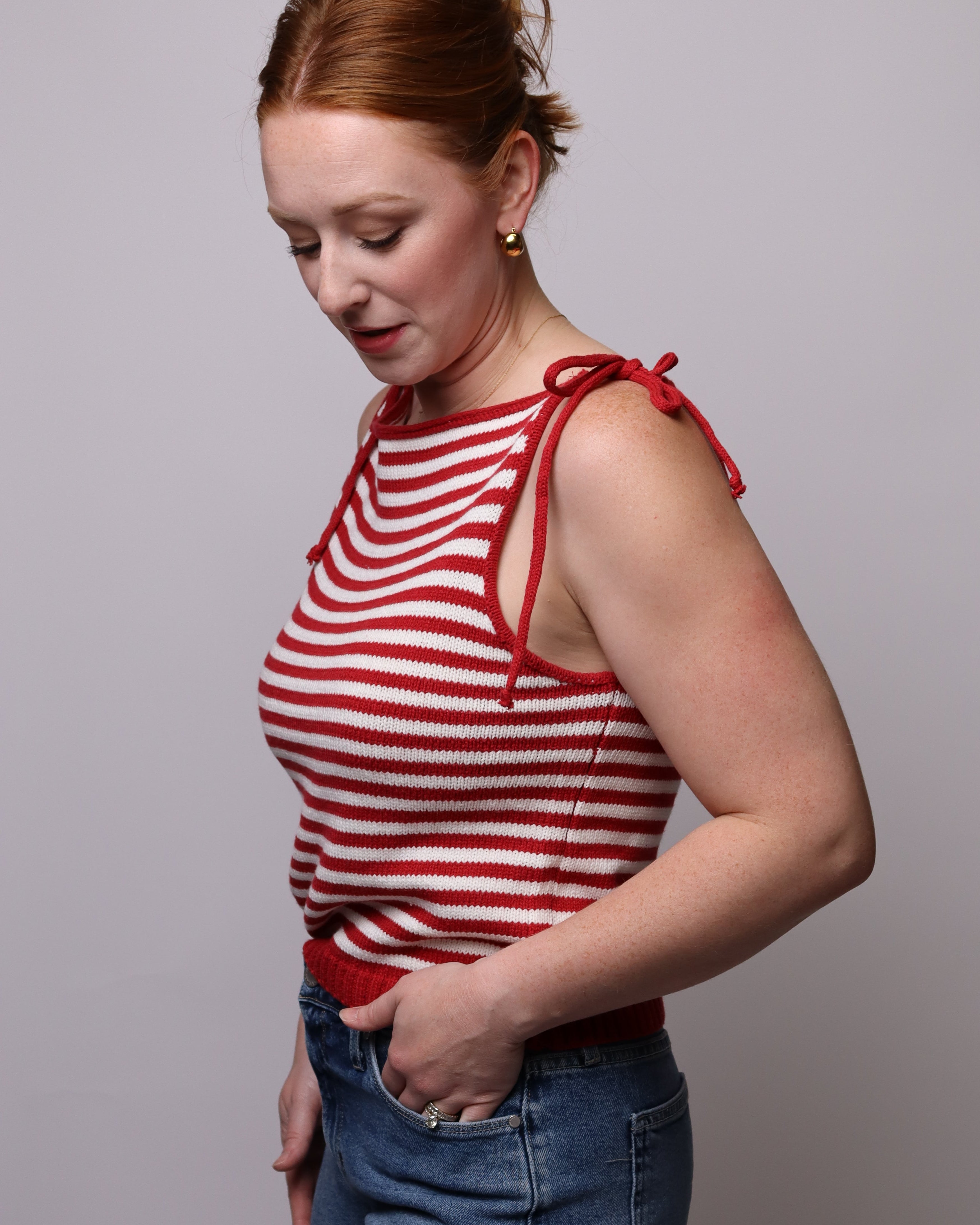 Woman wearing a red and white striped top and denim shorts against a plain background