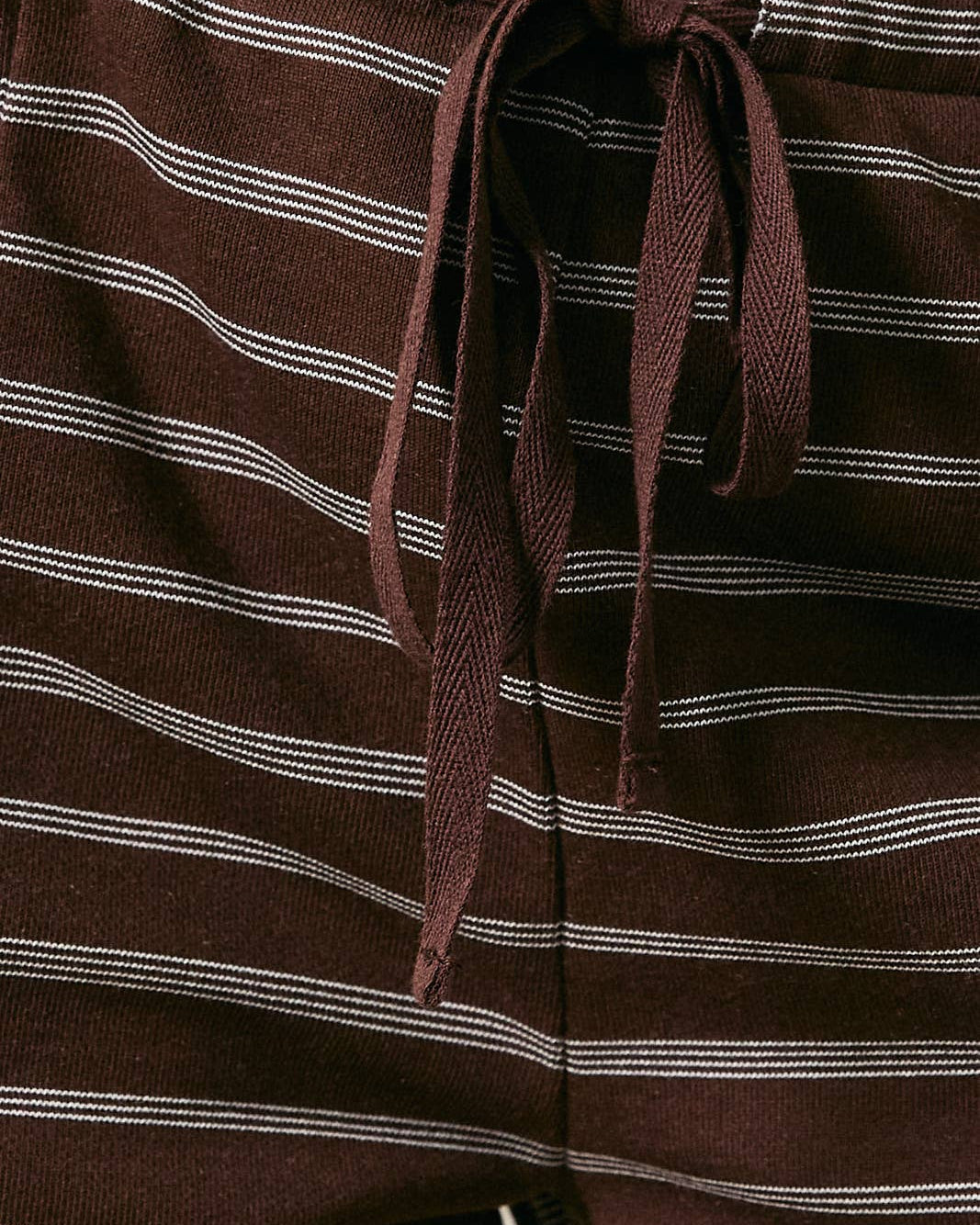 Close-up of brown striped pants with a tie waist.