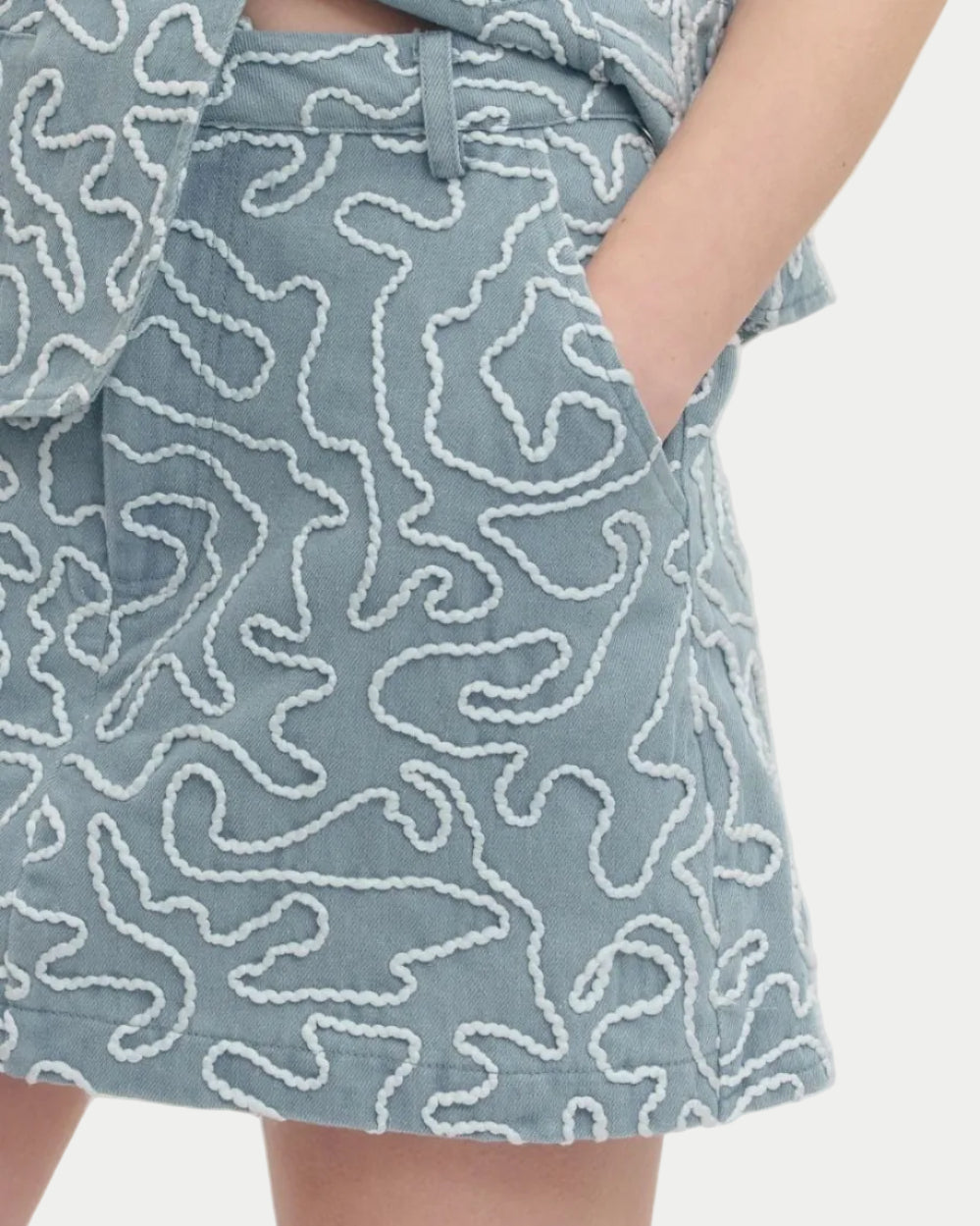 Person wearing light blue patterned shorts on a white background close up