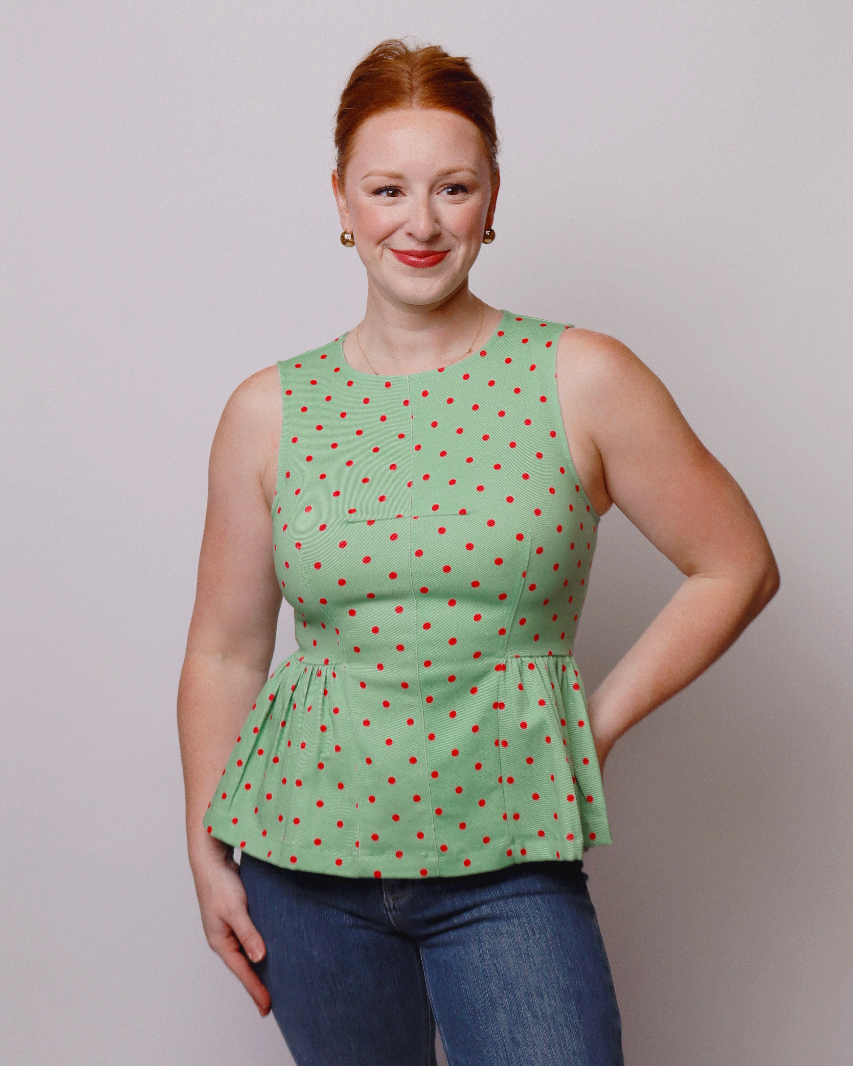 Woman wearing a green polka dot top against a plain background