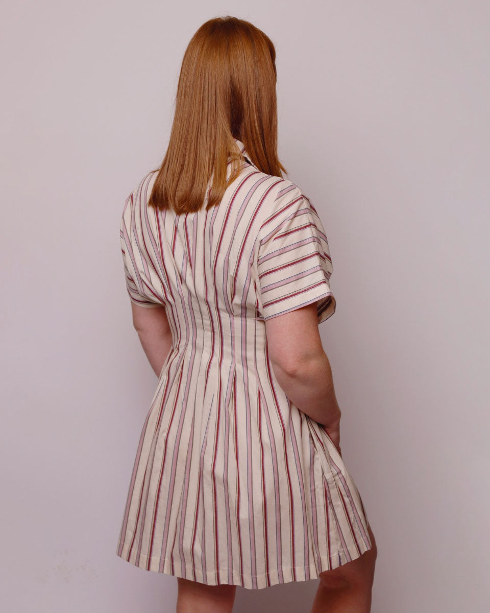 Woman wearing a striped dress from behind on a plain background