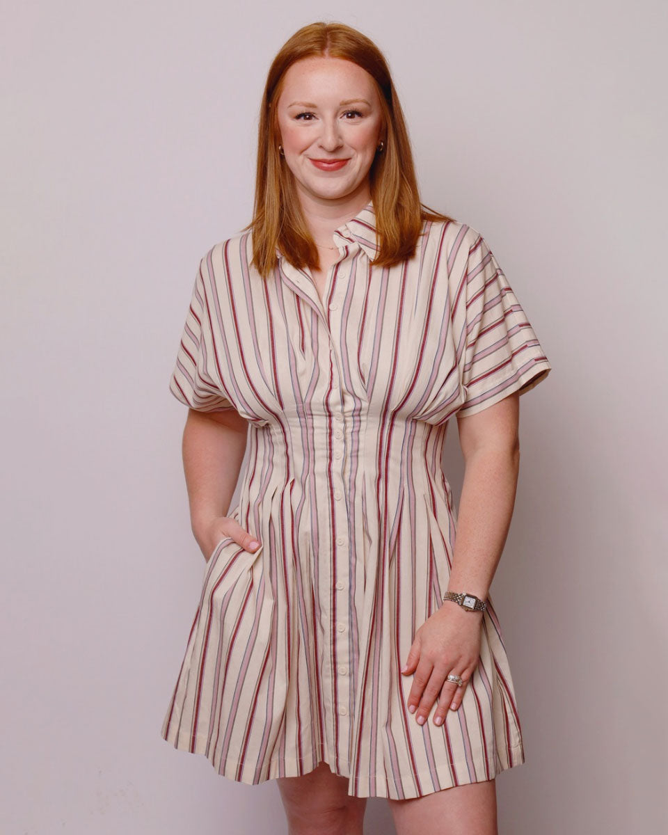 Woman wearing a striped dress against a plain background