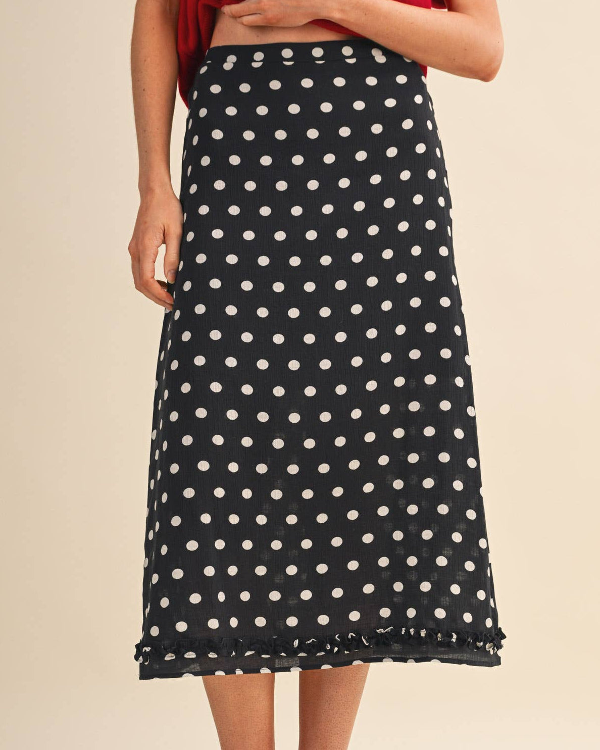 Model wearing a black polka dot skirt on a neutral background