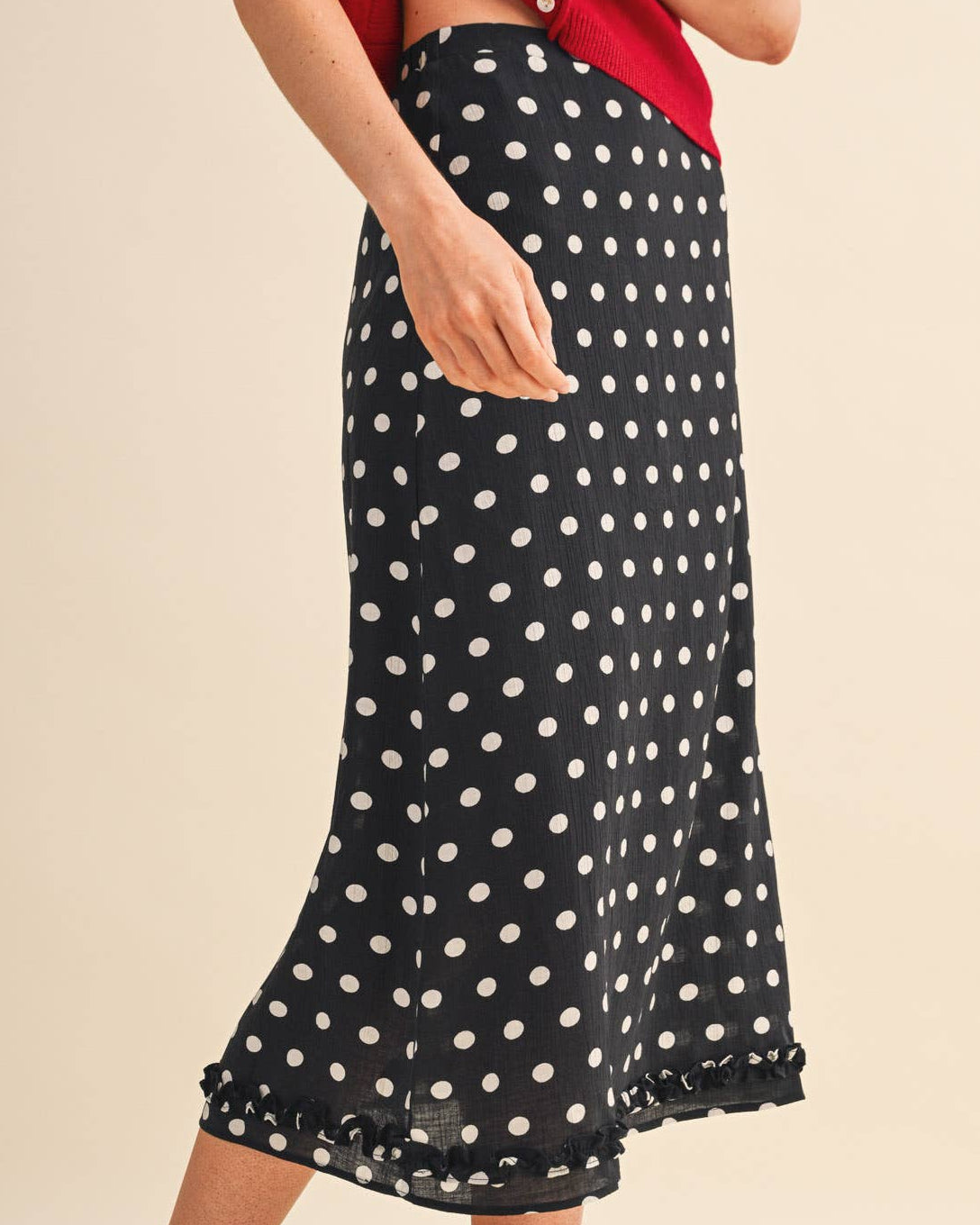 Model wearing a black polka dot skirt on a neutral background side view