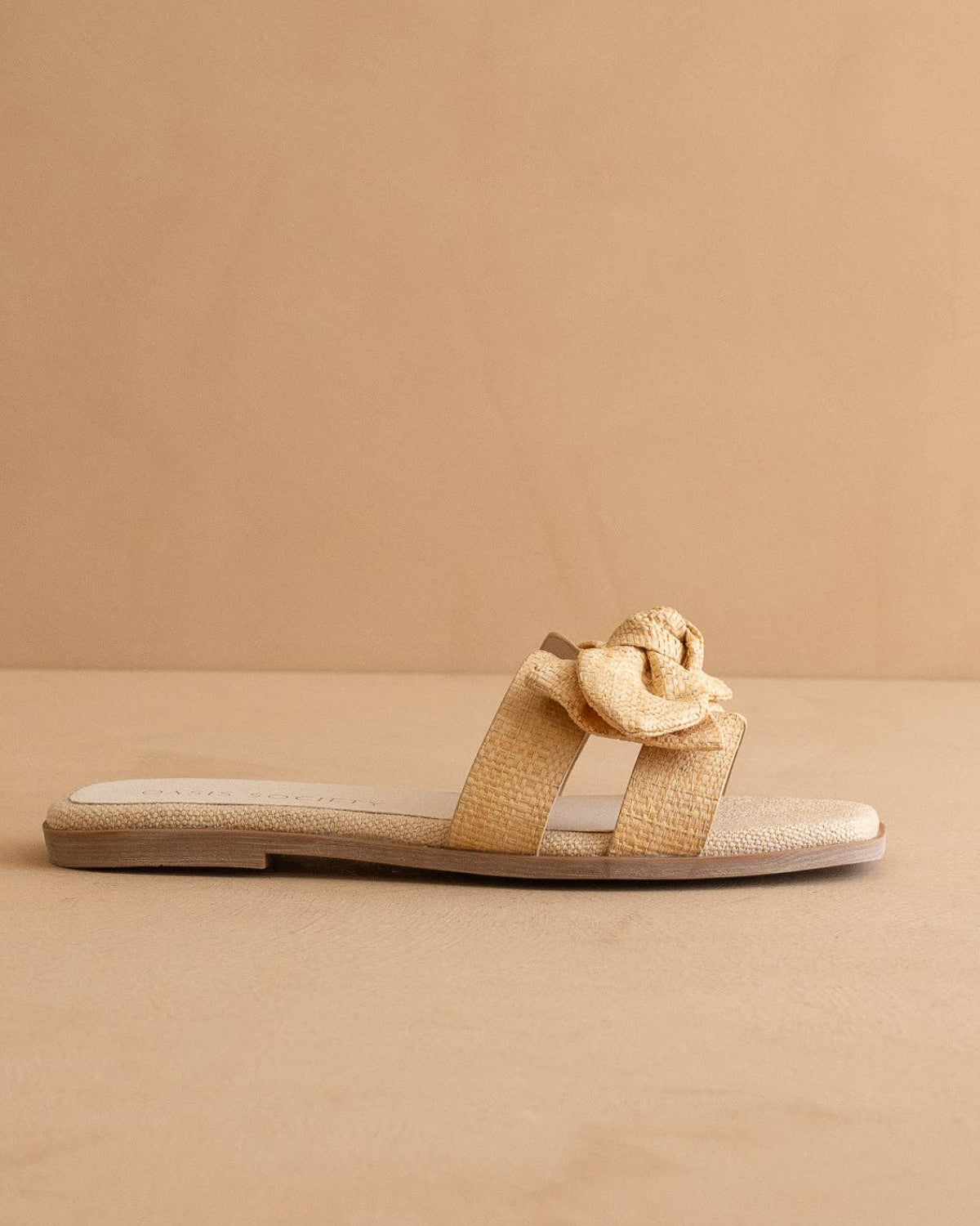 Beige sandal with a decorative bow on a beige background