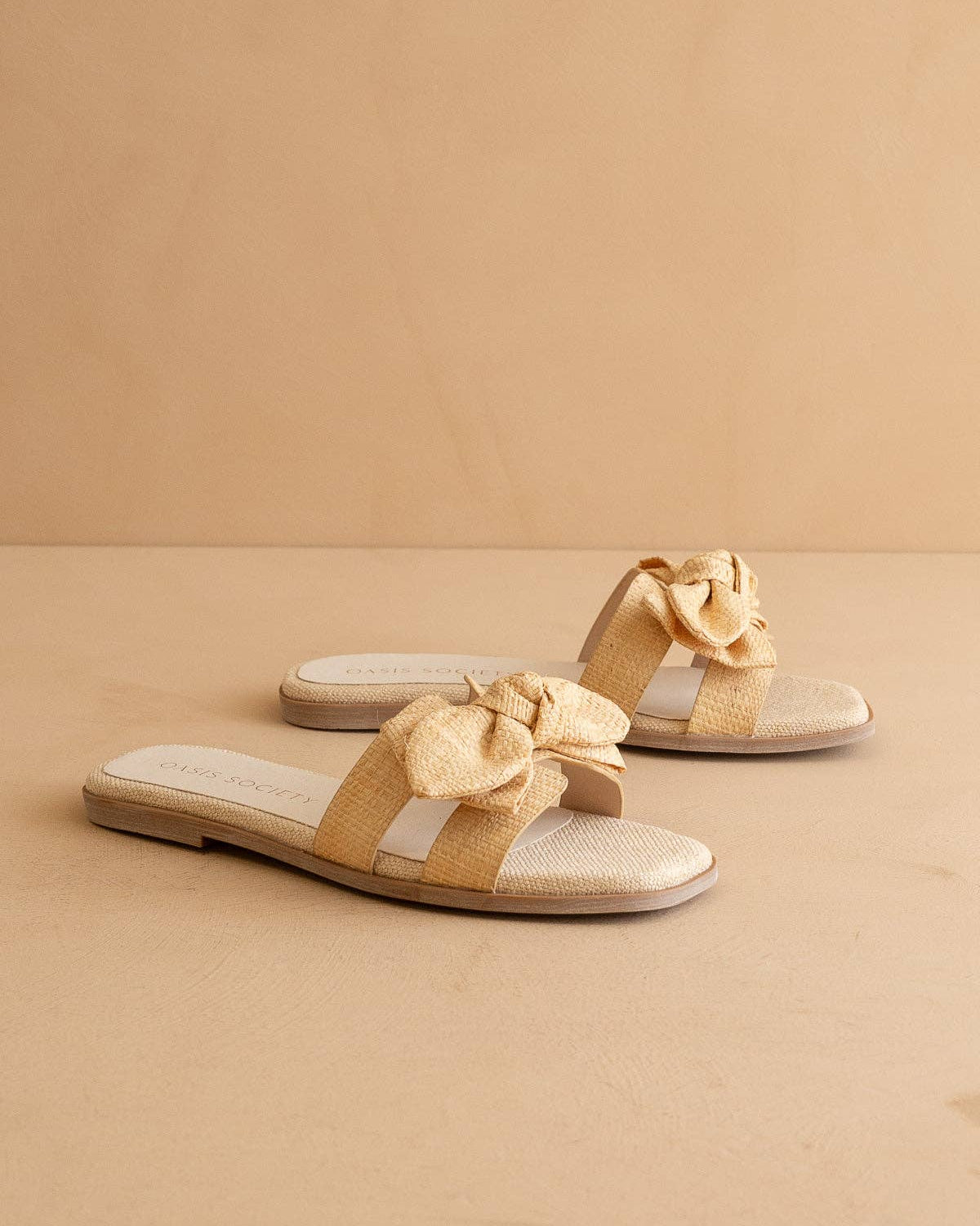 Beige sandals with bow details on a beige background