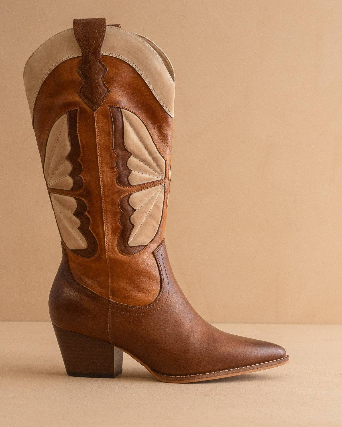 Brown cowboy boot with beige accents on a beige background