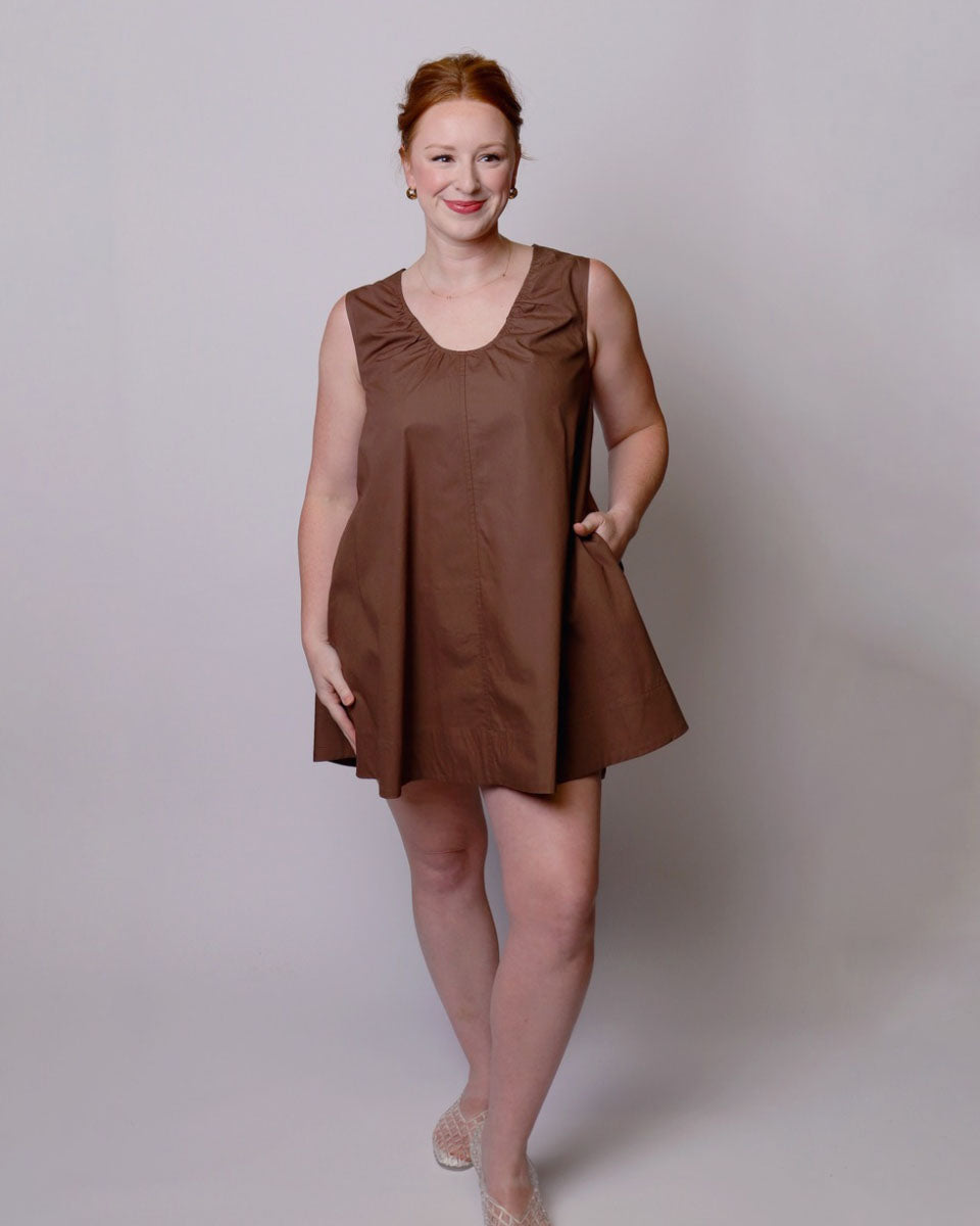 Woman wearing a brown dress against a plain background