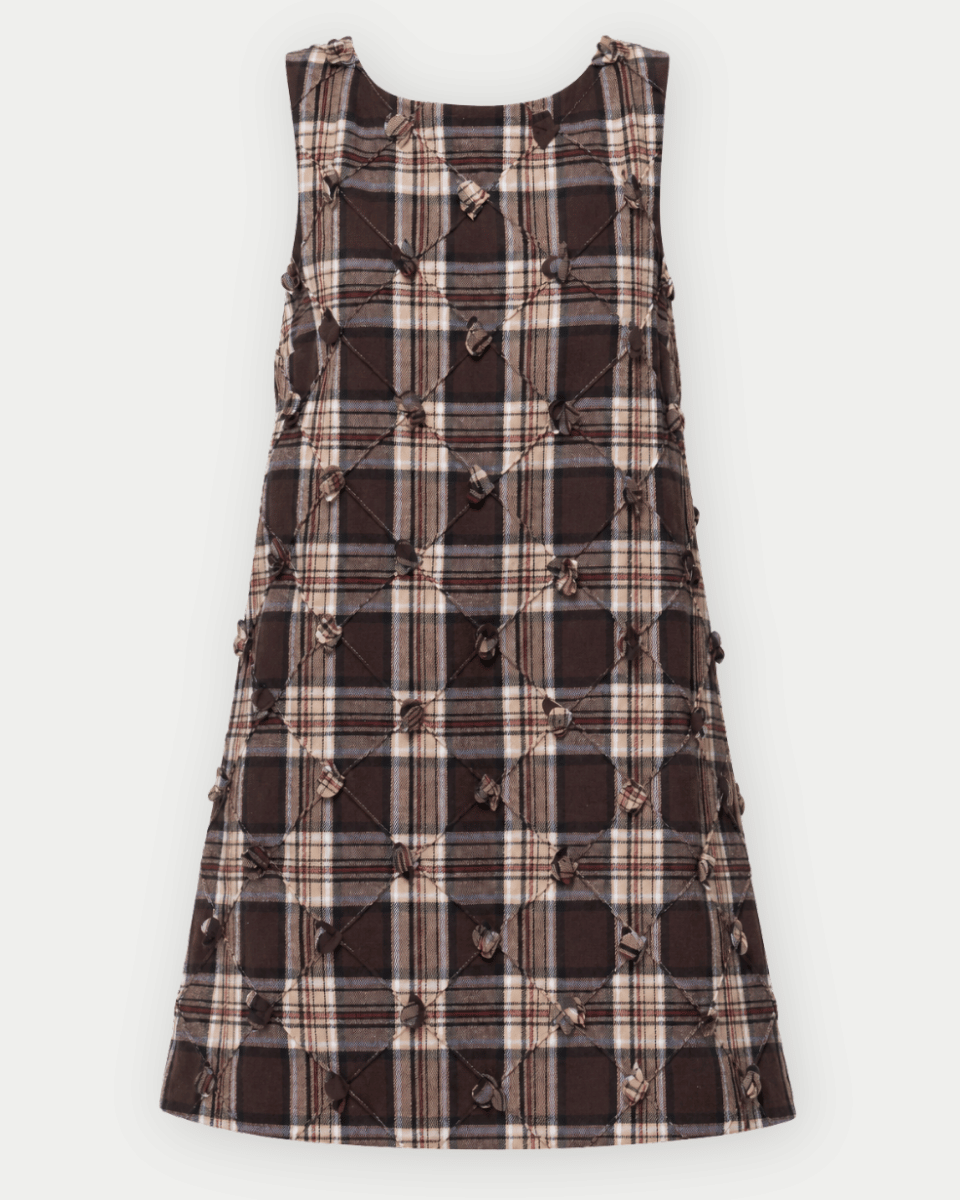 A sleeveless A-line dress featuring a brown, beige, and black plaid pattern, embellished with diamond-quilted stitching and knotted cord details.