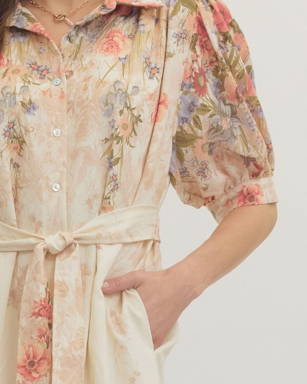 Floral patterned dress with a belt on a plain background