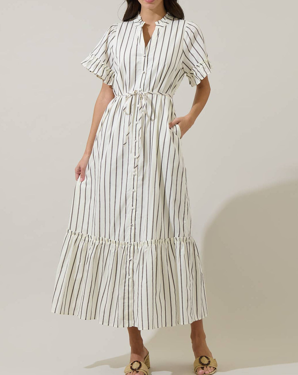 Woman wearing a white dress with black stripes against a plain background