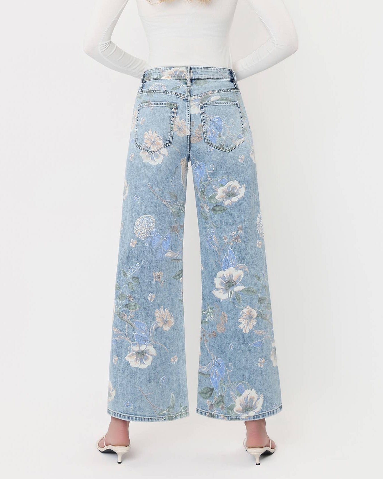 Person wearing light blue floral jeans on a white background
