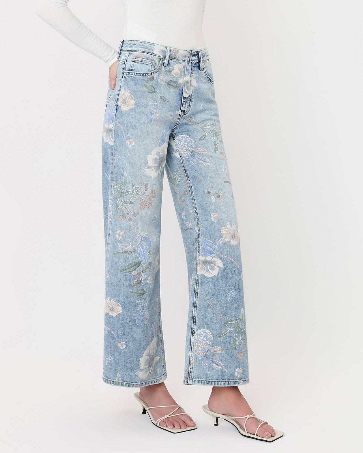 Woman wearing light blue floral jeans on a white background