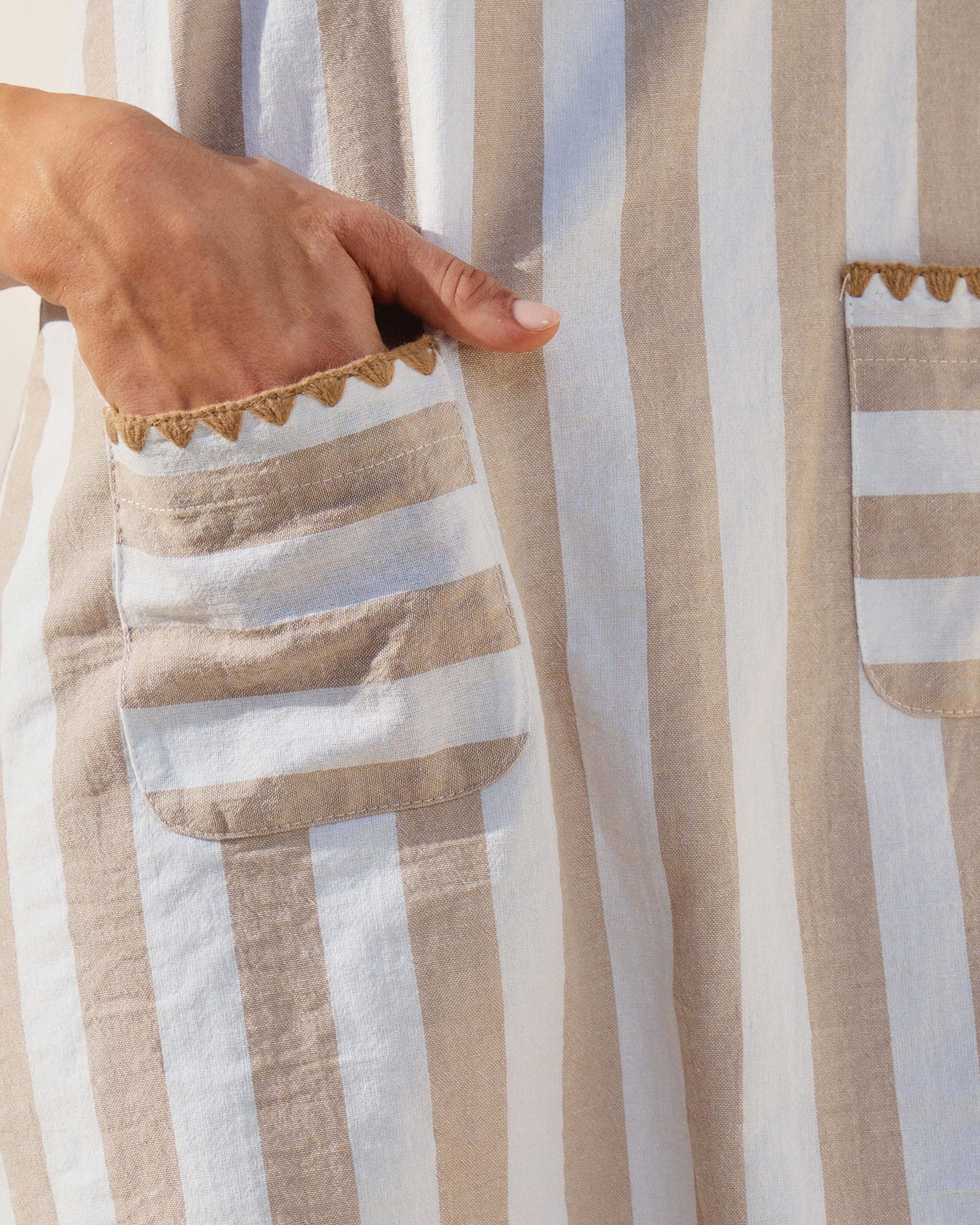 Vertical striped mini dress with whipstitch detail on a model with a neutral background.  close up