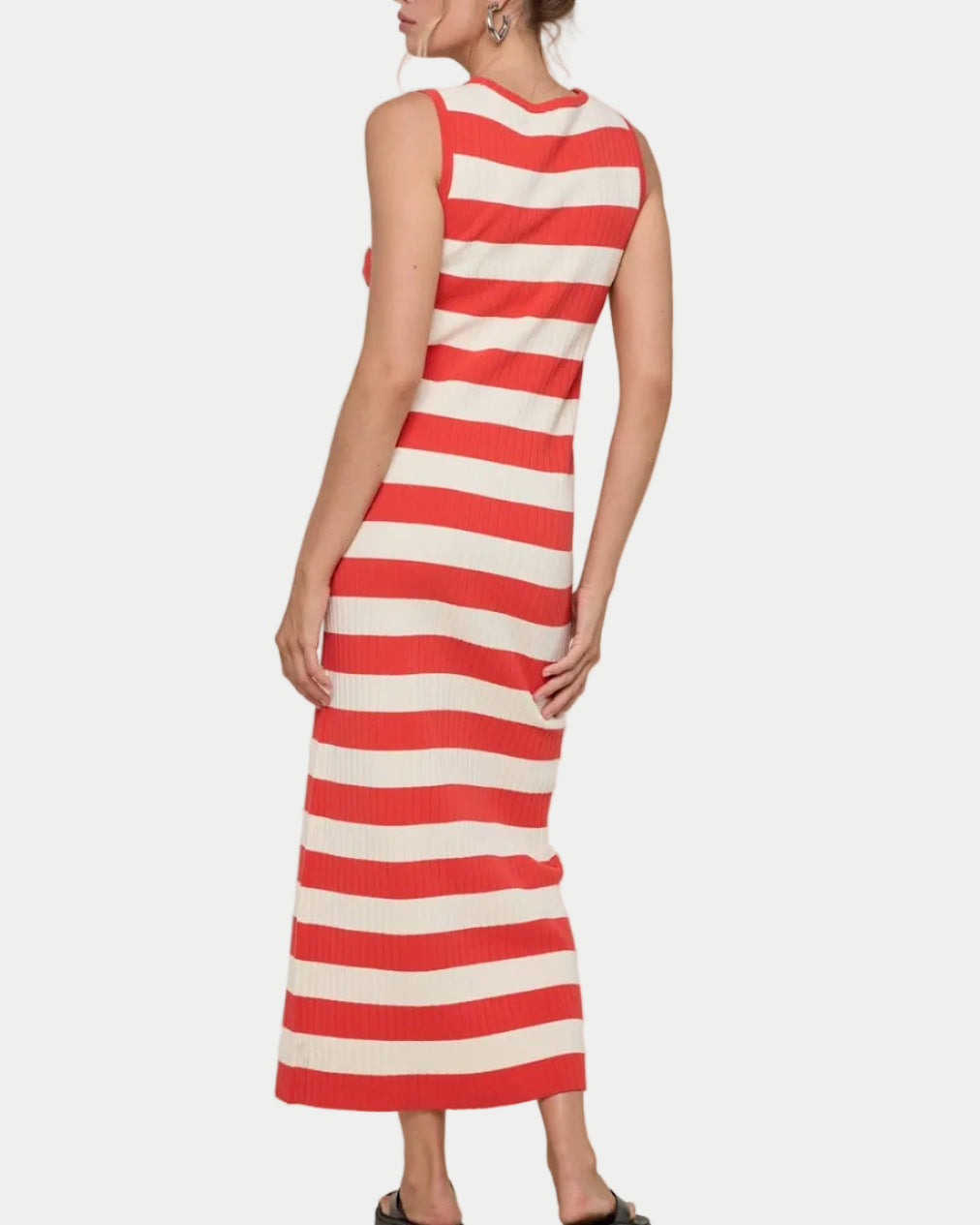 Woman wearing a papaya and white striped dress on a plain background